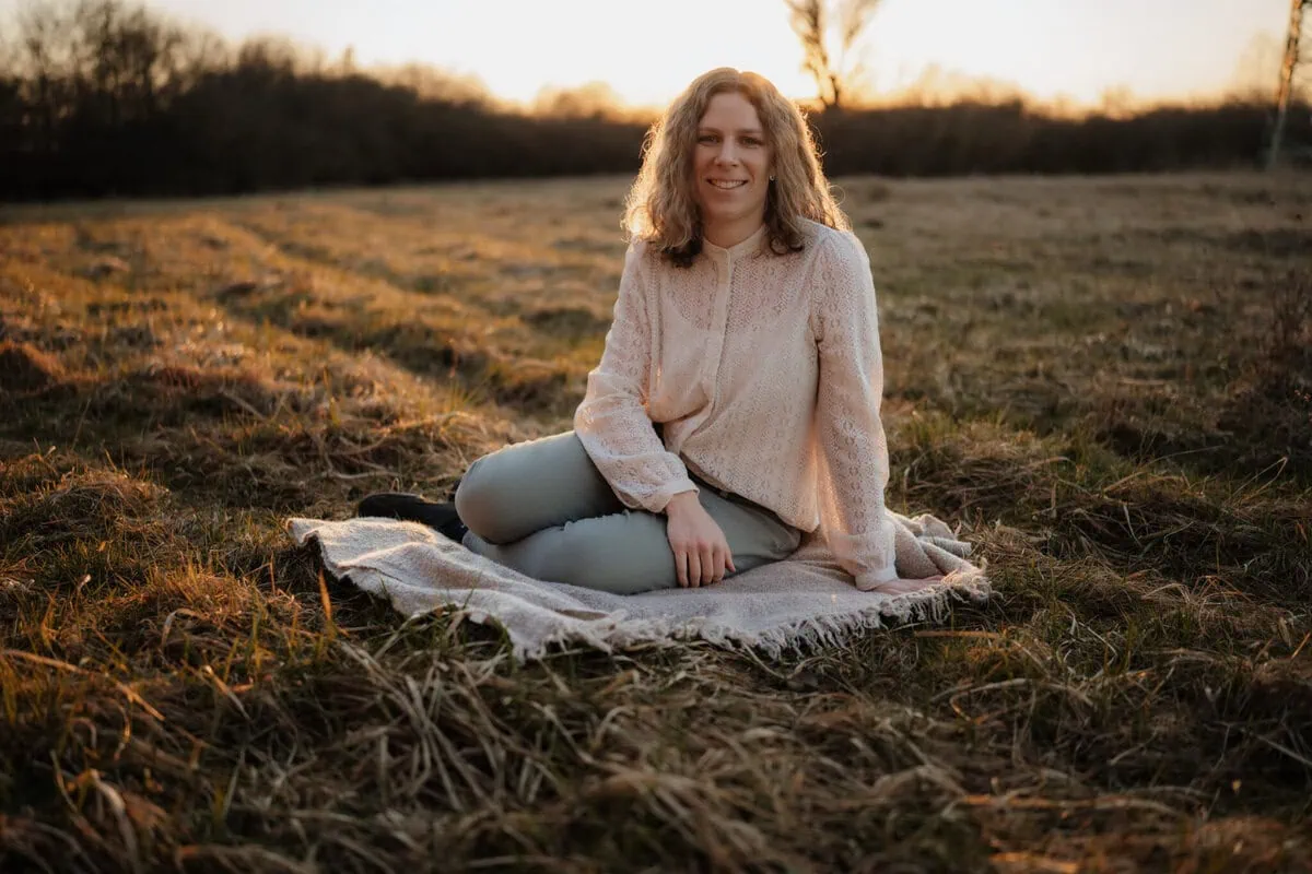 Fotoshooting W&uuml;rzburg Fotografin sitzt auf Decke auf Wiese im Sonnenuntergang